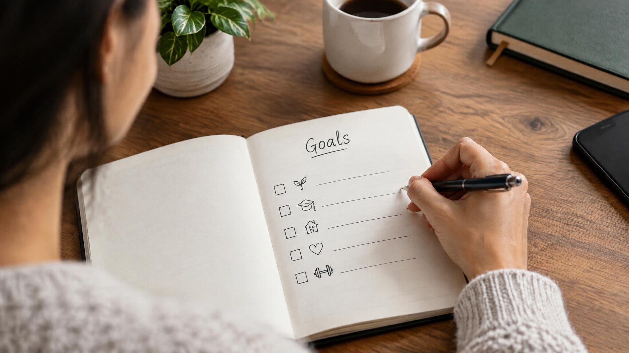 person writing goals in notebook
